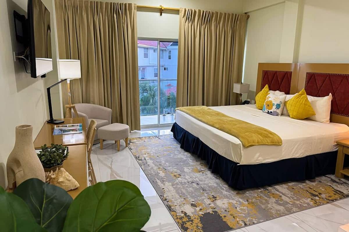 Ein Hotelzimmer mit Bett, Schreibtisch, Stuhl, Fernseher und Blick nach außen.