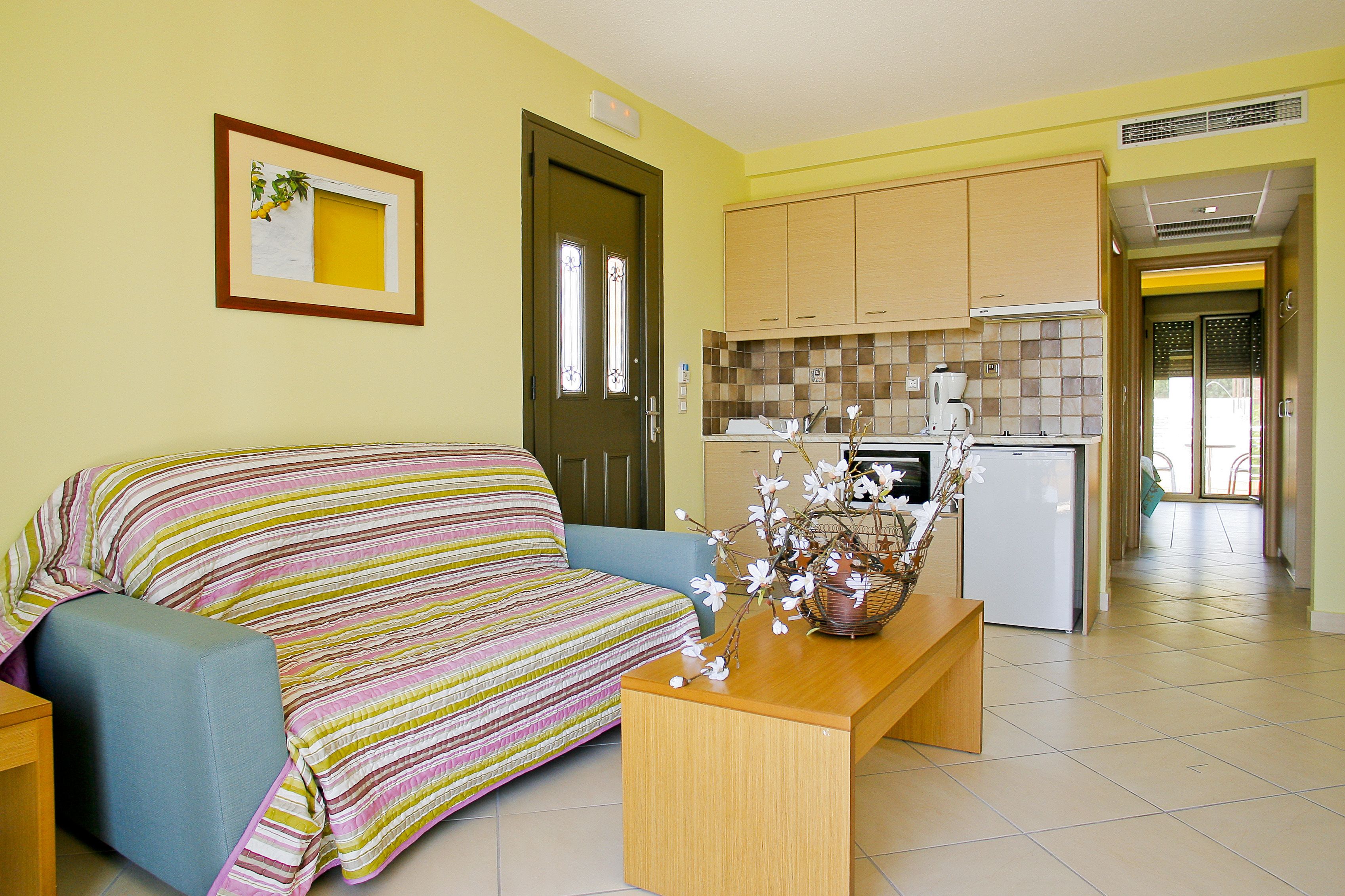 Un espacio habitable compacto con sofá, una mesita y kitchenette.