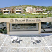 Un hotel con un letrero que dice 'Aegean Dream Hotel' y asientos al aire libre, con mesas y sillas.