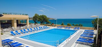 Una piscina con sillas de descanso azules y vista al mar.