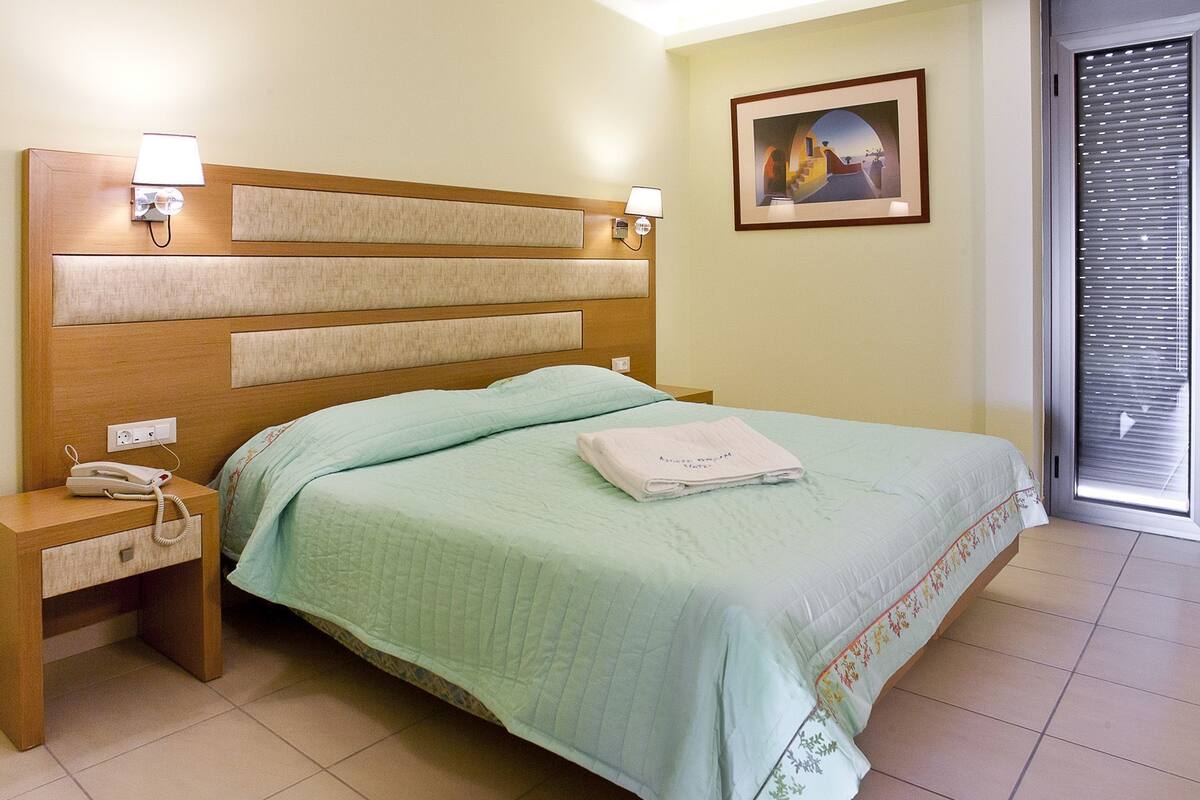 Une chambre d’hôtel avec un lit, une table de chevet, une lampe et un tableau au mur.