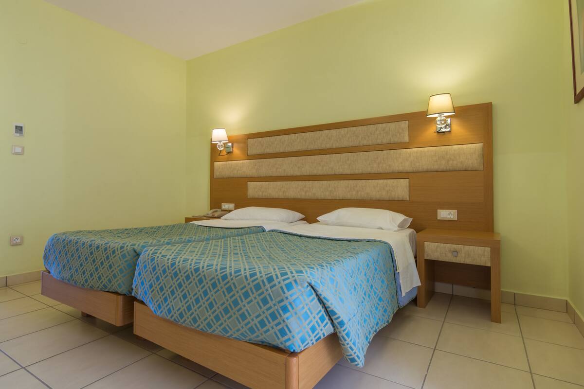 Une chambre d’hôtel avec un grand lit, deux tables de chevet et une tête de lit dotée d’un éclairage intégré.