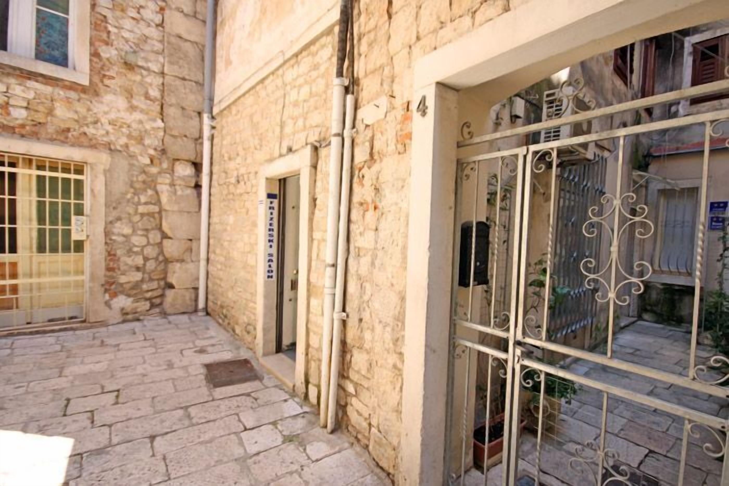 Un edificio de piedra con una reja de metal y un patio estrecho.