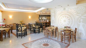 A restaurant with multiple tables and chairs, a bar area, and a decorative ceiling. - Kyveli Apartments (Chios)