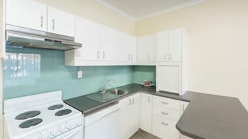 A kitchen with white cabinets, a stainless steel stove, a dishwasher, and a grey countertop.