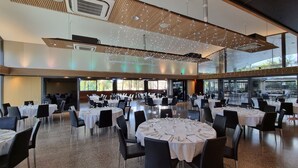 A spacious dining area with round tables, black chairs, and string lights. - McLaren Vale Motel & Apartments (McLaren Vale)