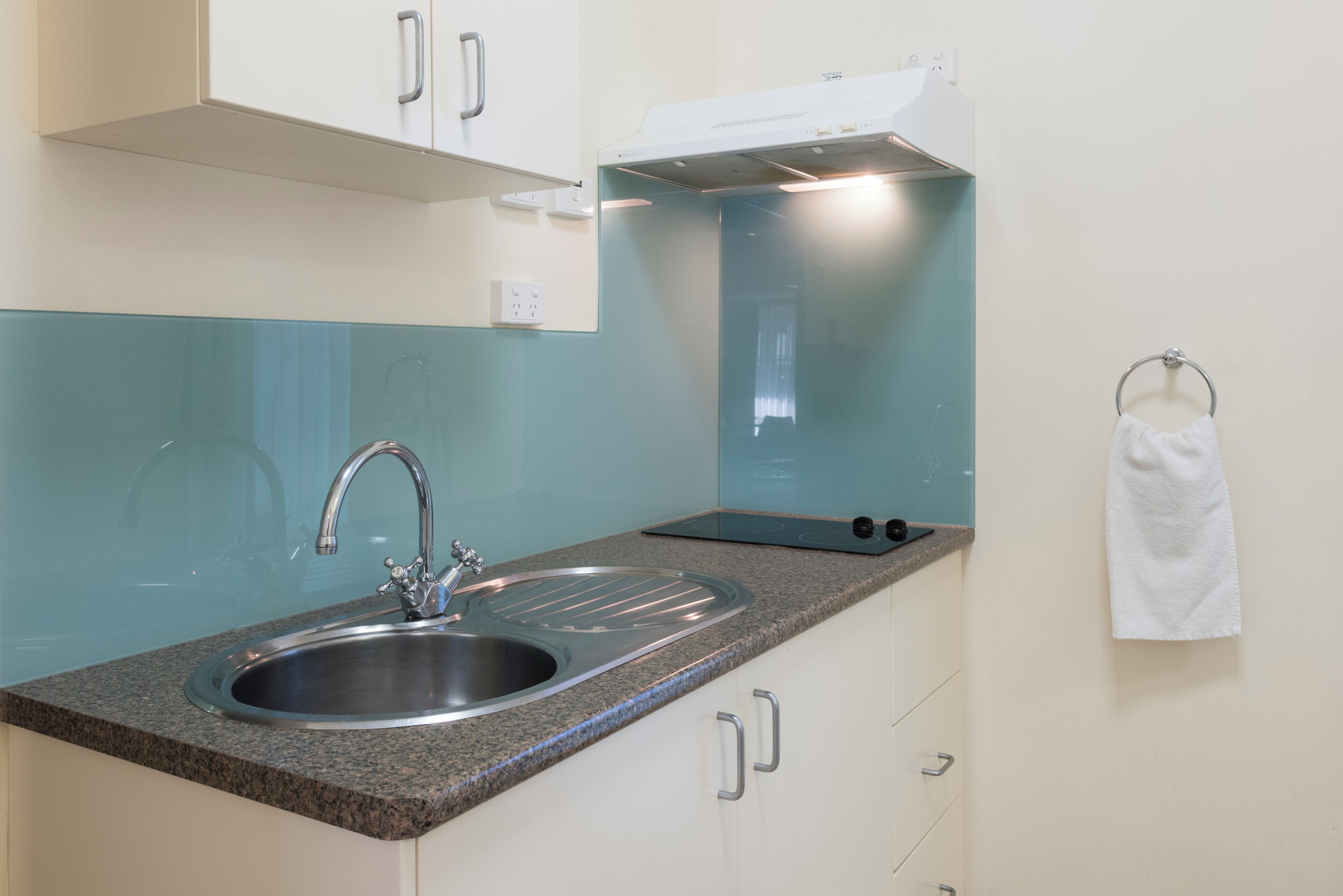 A kitchen with a double sink, a stove, and a towel hanging on the wall.