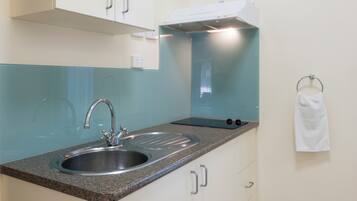 A kitchen with a double sink, a stove, and a towel hanging on the wall.
