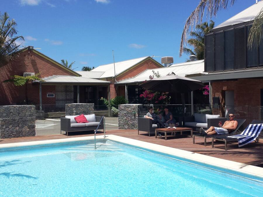 A poolside area with a pool, lounge chairs, and a covered seating area with umbrellas.