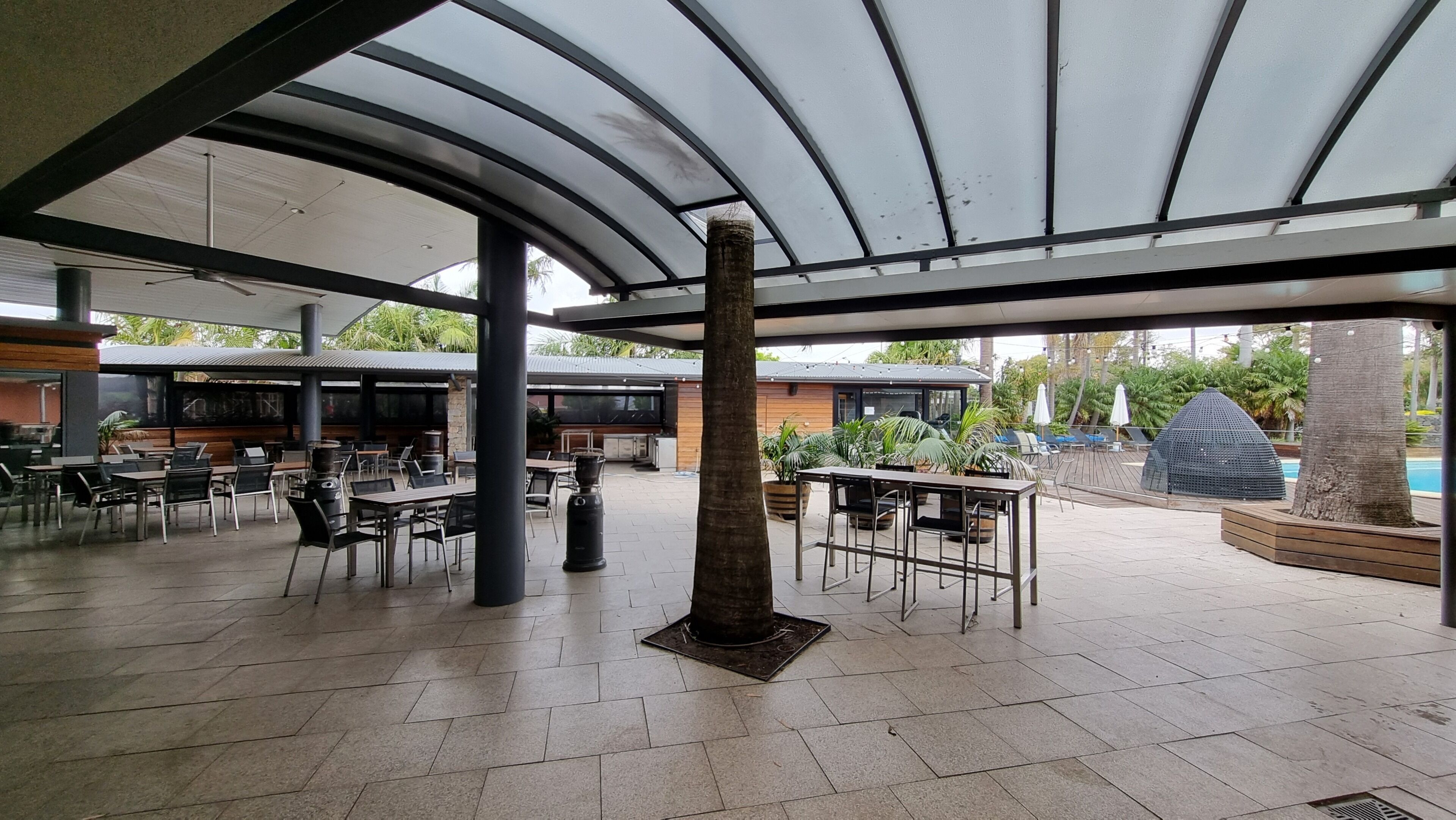 An outdoor patio area with tables and chairs, a grill, and a covered seating area.