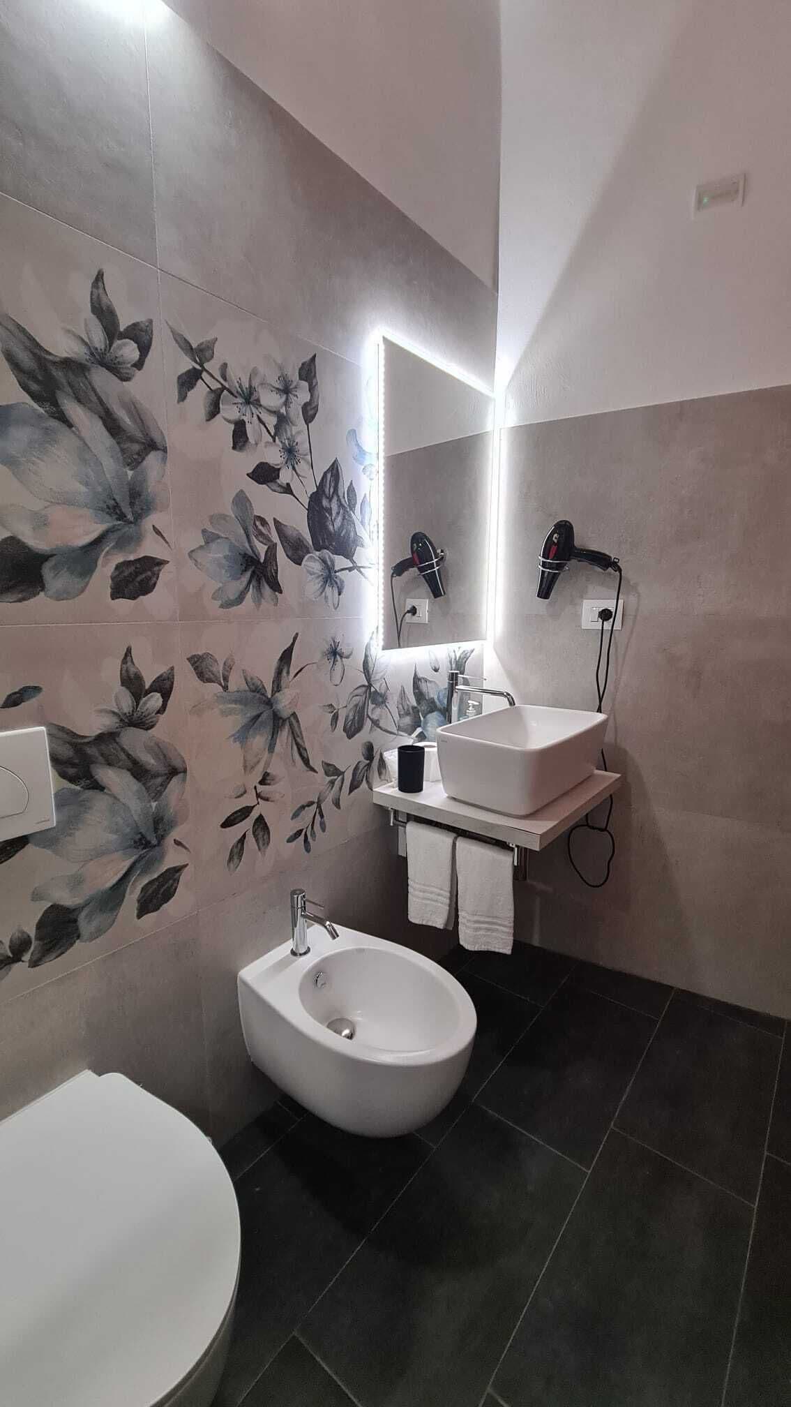 Ein Badezimmer mit Bidet, Waschbecken, Spiegel und Fön.