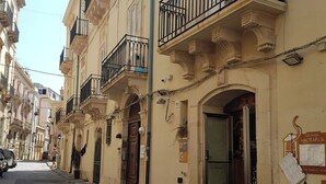 A street view of a row of traditional buildings with balconies, a clear sky, and a signboard on the building.