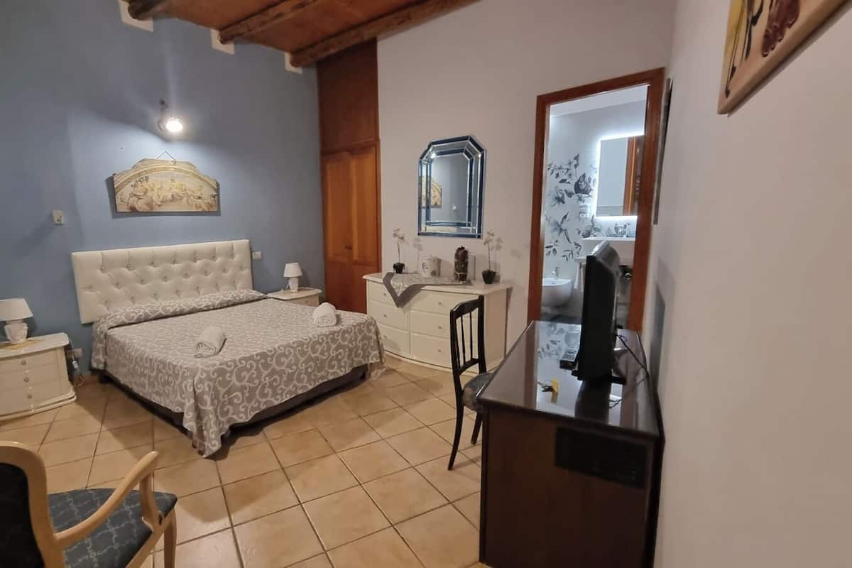 A bedroom with a bed, bedside tables, a dresser, a chair, a desk, and a mirror.