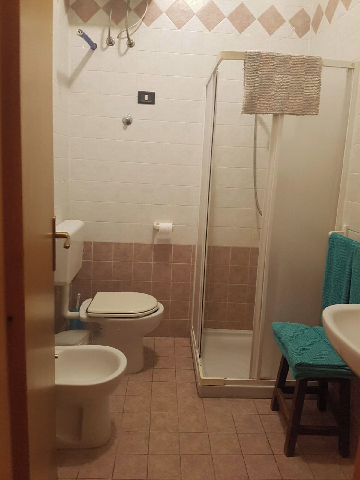 A bathroom with two toilets, a shower, and a sink.