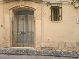 Μια πρόσοψη κτιρίου με μια μεγάλη, αψιδωτή είσοδο, μια πόρτα με κάγκελα και ένα παράθυρο με κάγκελα.