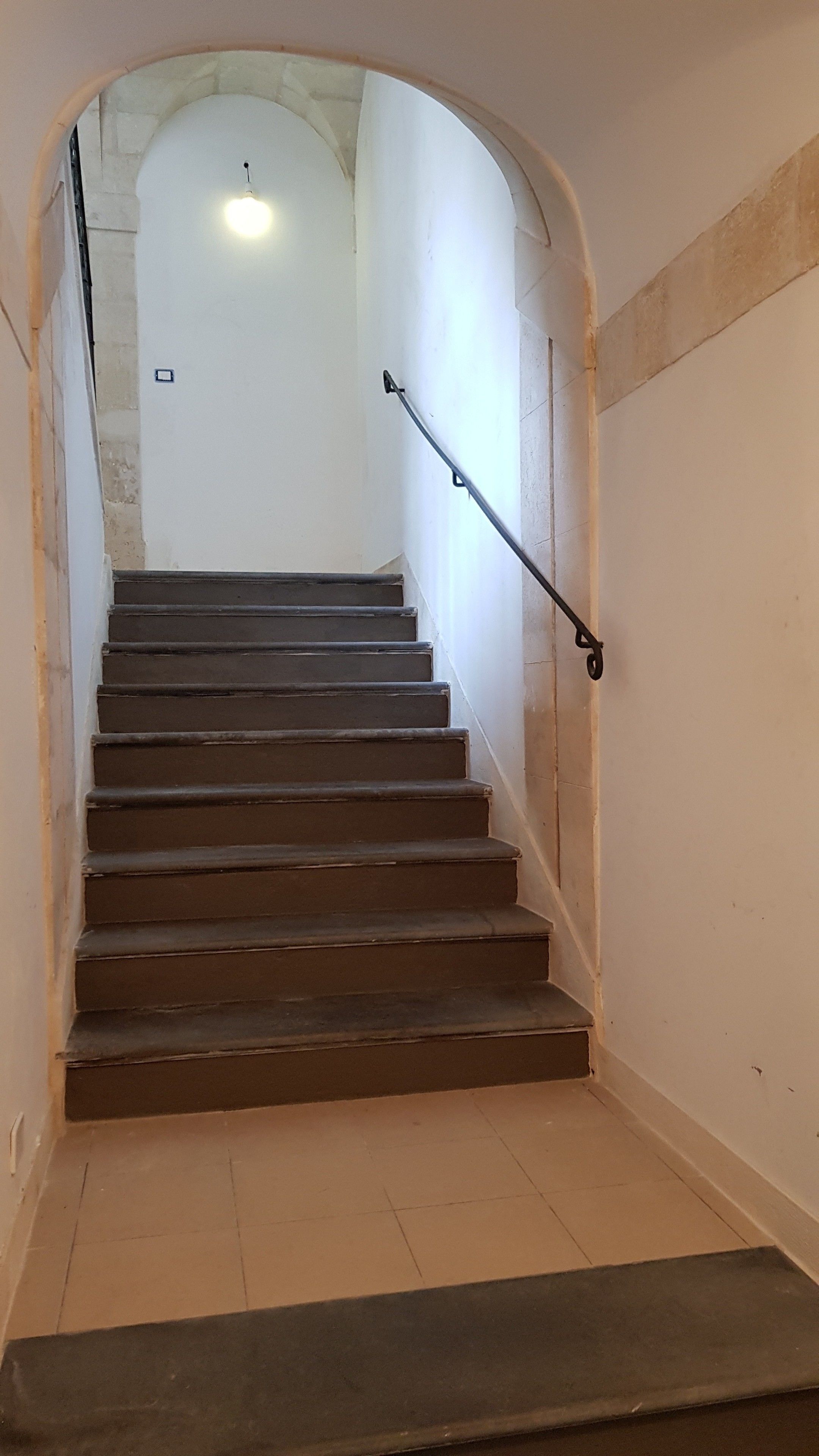 A staircase with a handrail, leading to a landing with a light fixture.
