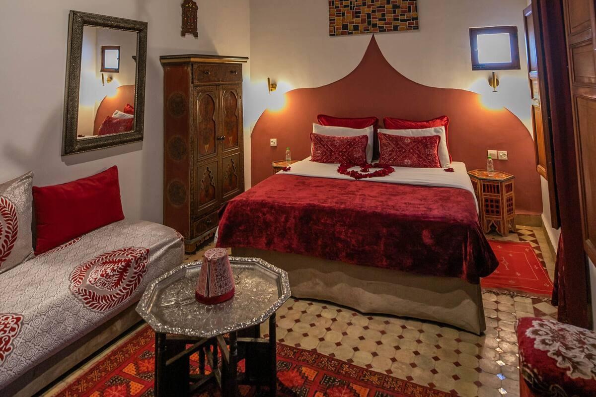 A bedroom with a bed, a sofa, a small table, a cabinet, and a decorative ceiling.