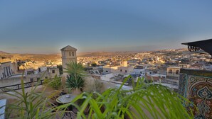 A cityscape with a prominent tower, terraced rooftops, and a view of distant hills. - Riad Les Idrissides (Fes)