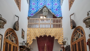 A traditional Moroccan interior with a courtyard, wooden doors, patterned textiles, and a small seating area. - Riad Les Idrissides (Fes)