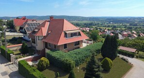 Una casa grande con techo rojo, paneles solares y un jardín bien cuidado.