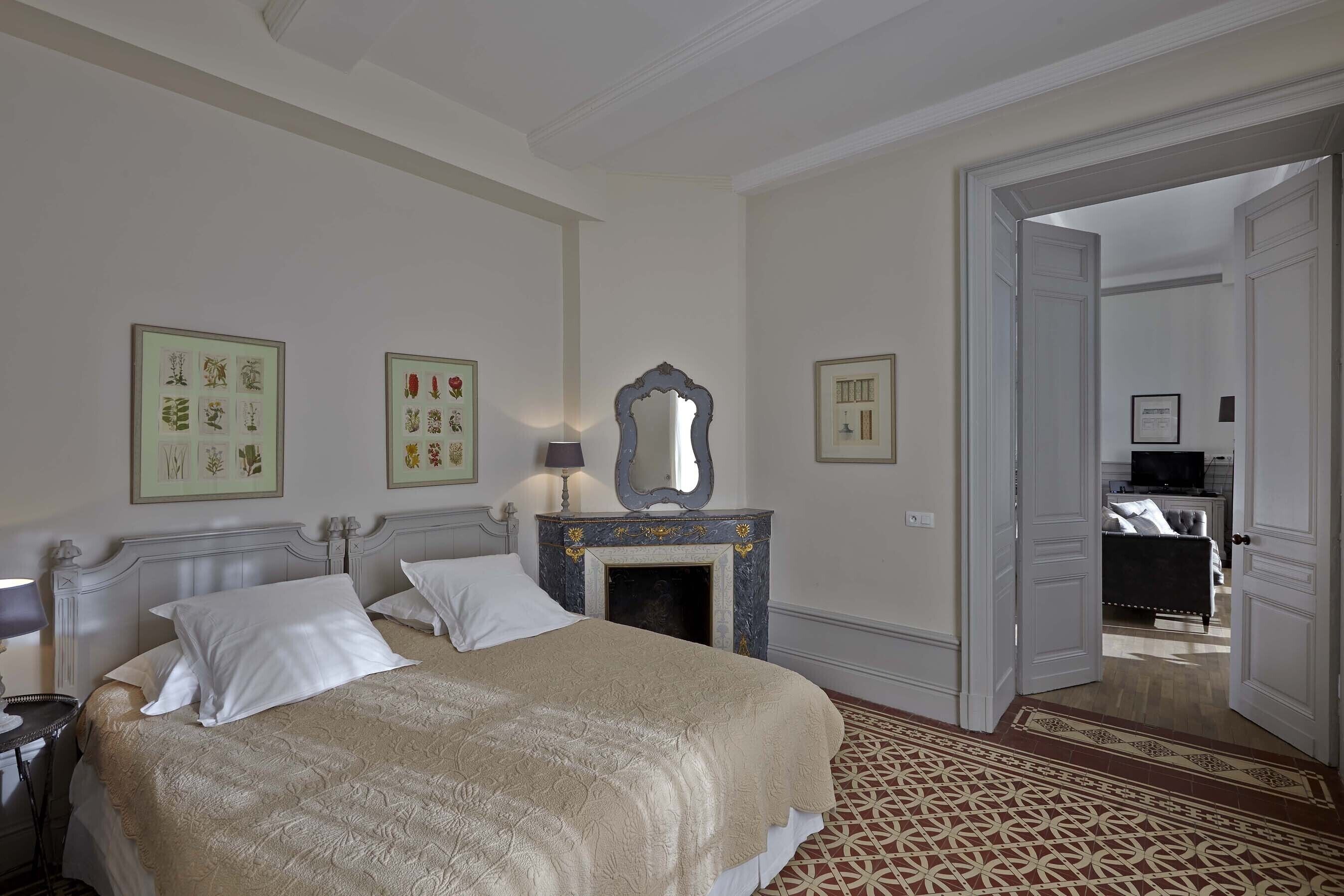 Un dormitorio de hotel con una cama grande, una chimenea y cuadros enmarcados en la pared.