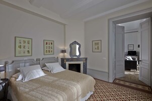 Un dormitorio de hotel con una cama grande, una chimenea y cuadros enmarcados en la pared.