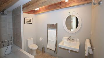 A bathroom with a bathtub, toilet, sink, and a wooden ceiling beam.