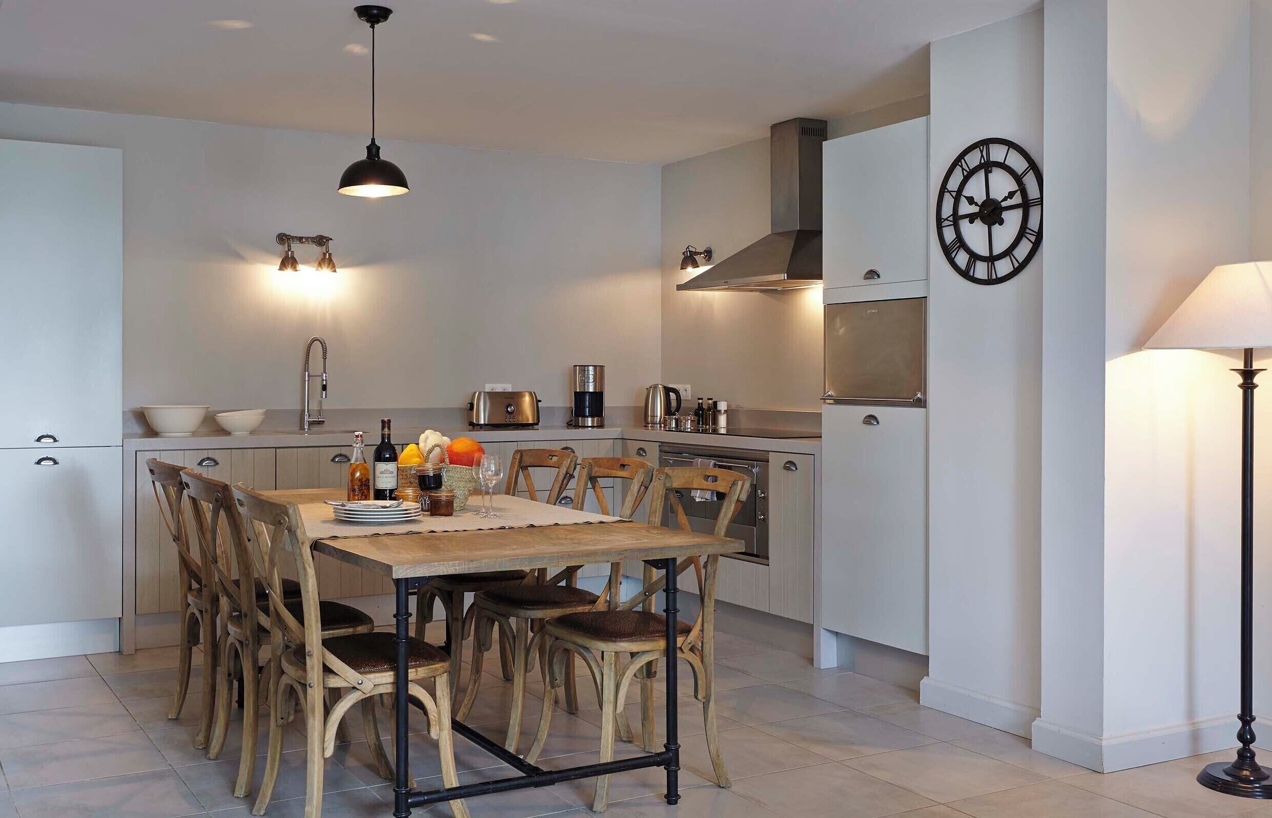 A modern kitchen with a dining table, chairs, and various appliances.
