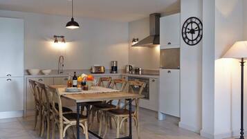 A modern kitchen with a dining table, chairs, and various appliances.