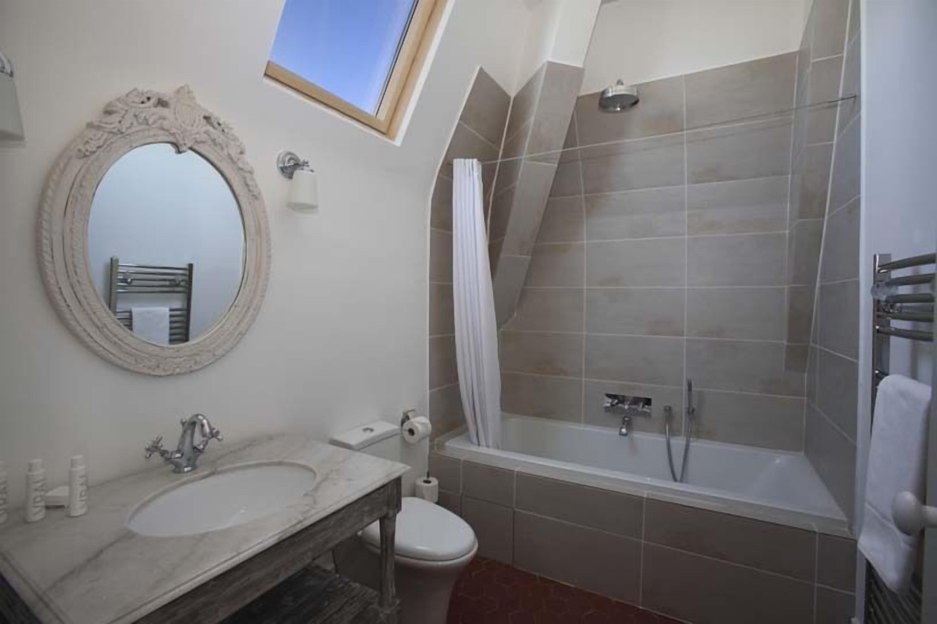 A bathroom with a marble sink, a toilet, a bathtub, and a shower.