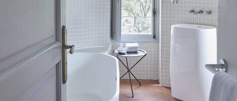 Un baño con una bañera grande, una ventana y un lavamanos.