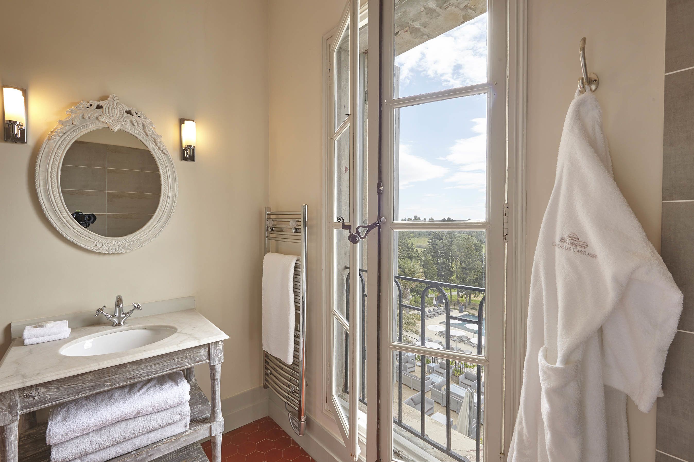 Un baño con un espejo grande, un lavabo, un perchero para toallas y una ventana con vistas al exterior.
