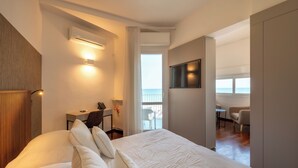 A modern hotel room with a large bed, a desk with a chair, a flat-screen TV, and a balcony with a view of the sea. - HR Resort (Senigallia)