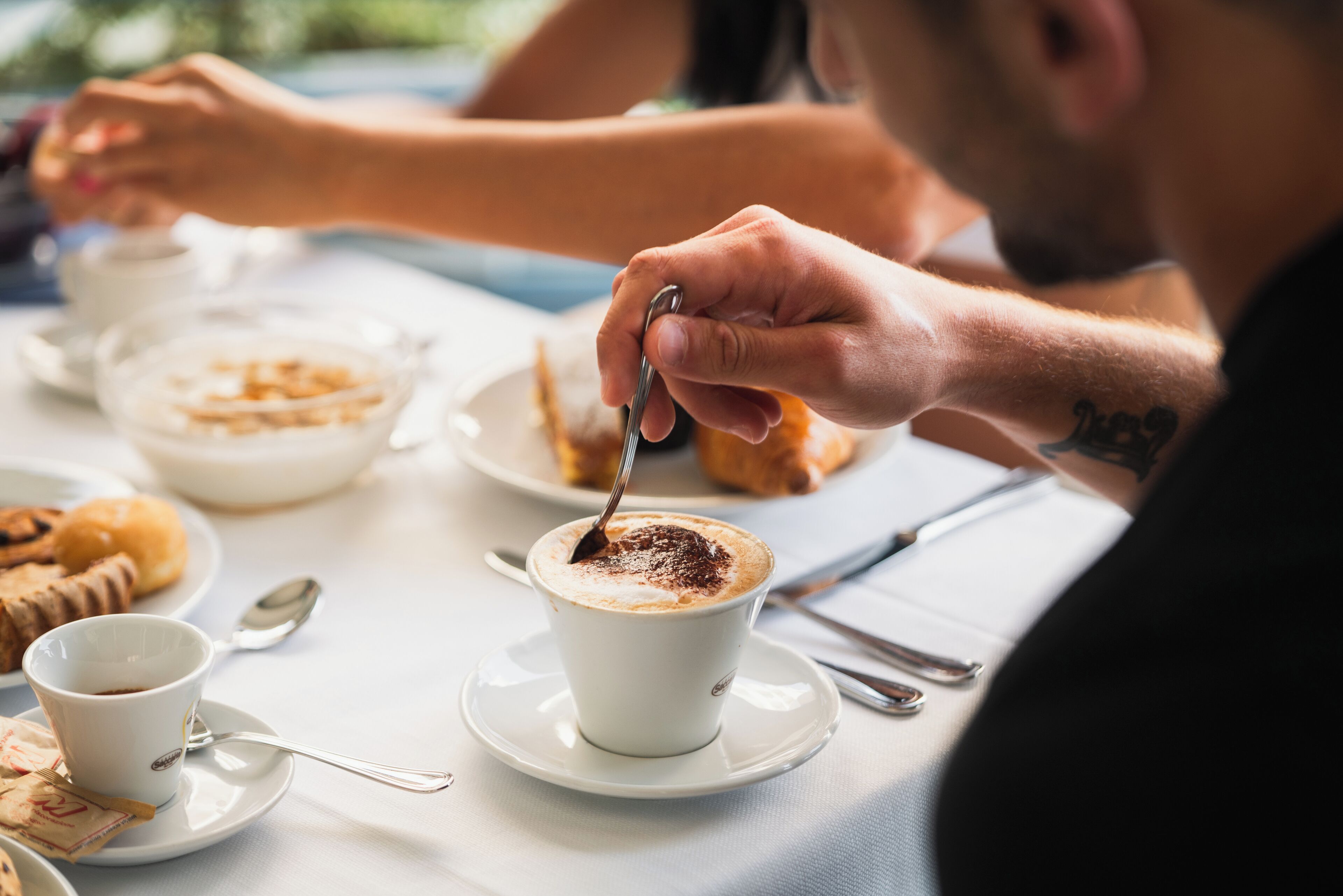 Ein Esstisch mit einer Kaffeetasse, Gebäck und einem Löffel.