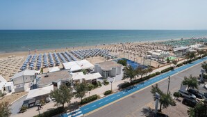 A beach resort with rows of beach umbrellas, a parking area, and a road leading to the beach. - HR Resort (Senigallia)