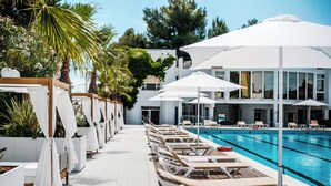 A poolside area with sun loungers and umbrellas, surrounded by white buildings and greenery. - HR Resort (Senigallia)