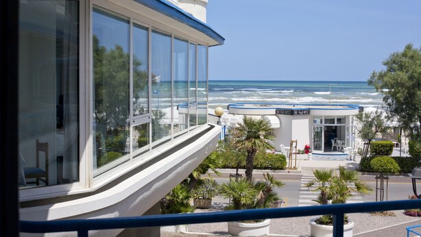 A hotel with a balcony overlooking the sea, a pool area with lounge chairs, and a building with a blue and white color scheme. - HR Resort (Senigallia)