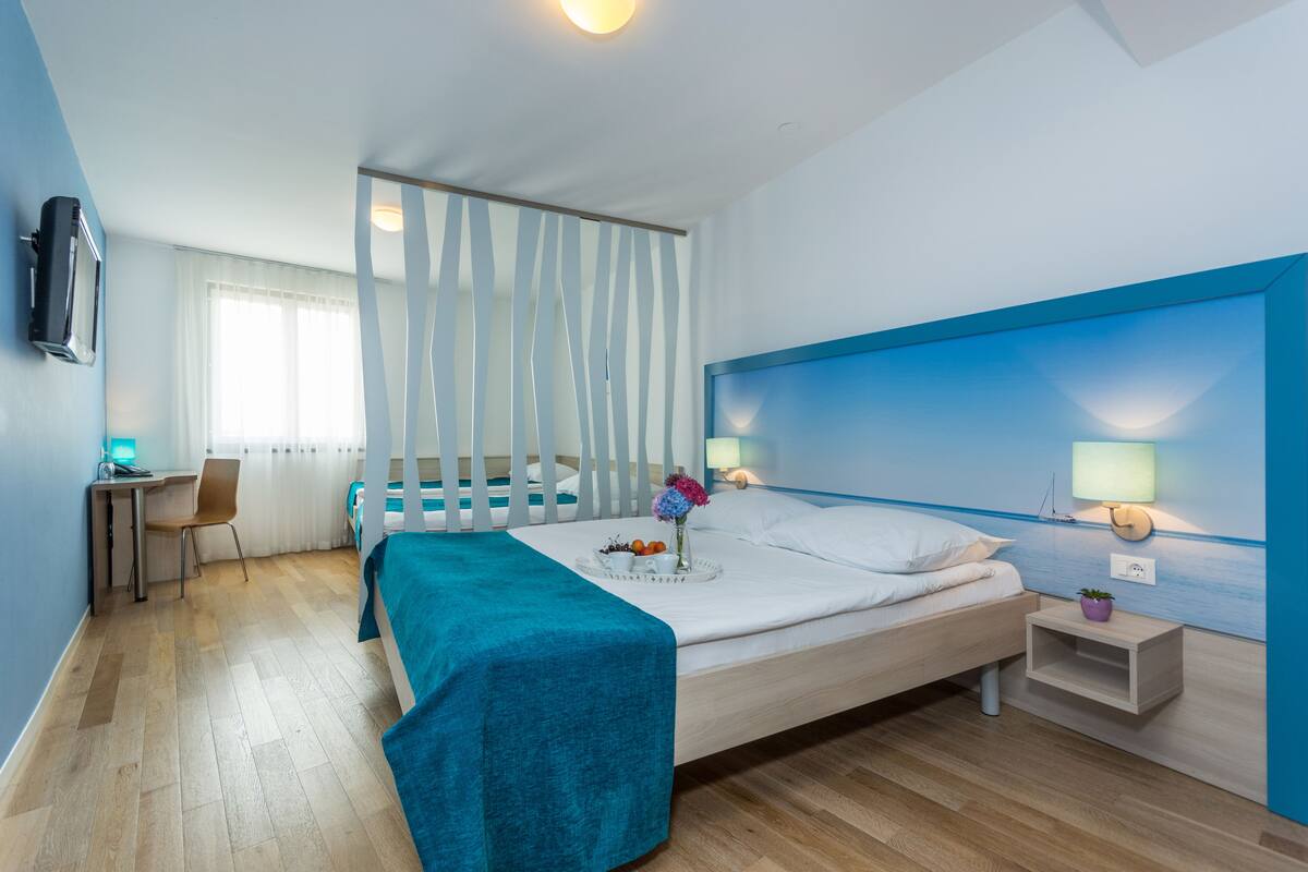 A modern hotel room with a bed, a desk, and a chair.