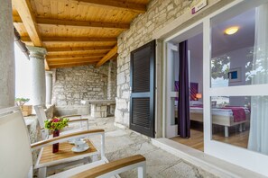 A stone building with a wooden ceiling and a room with a bed and curtains. - Hotel Vista (Vrsar)