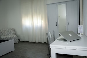Una habitación con una cama, un escritorio con una computadora portátil, una silla y un armario.