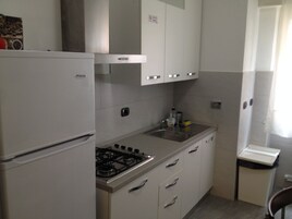 Una cocina compacta con refrigerador, estufa y alacenas.