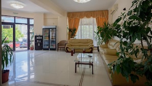 A hotel lobby with a reception desk, seating area, and a large potted plant. - Coral Eforie Nord (Eforie)