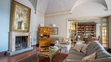 A spacious living room with a fireplace, a large bookshelf, a comfortable sofa, and a coffee table.