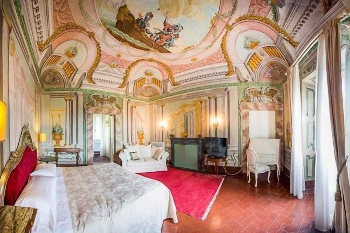 Una lujosa habitación de hotel con una cama grande, televisión, escritorio y alfombra roja.