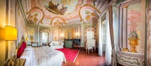 Una lujosa habitación de hotel con una cama grande, televisión, escritorio y alfombra roja.