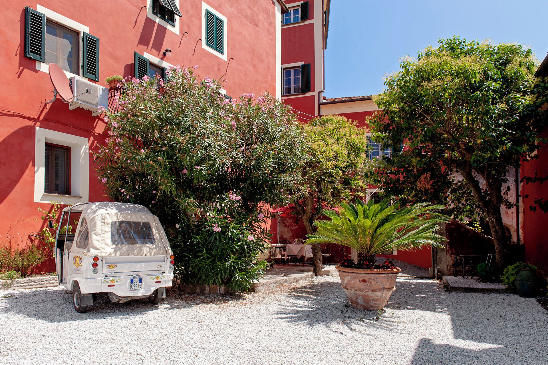 A white van parked in front of a red building with multiple windows and shutters.