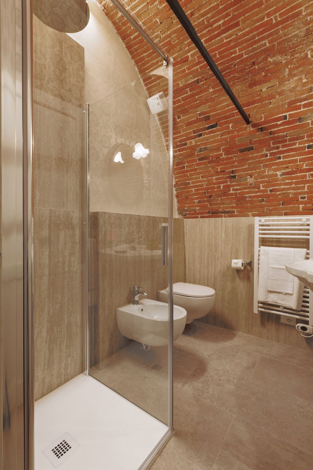A modern bathroom with a glass-enclosed shower, a sink, and a toilet. The walls are made of wood, and there is a brick ceiling.