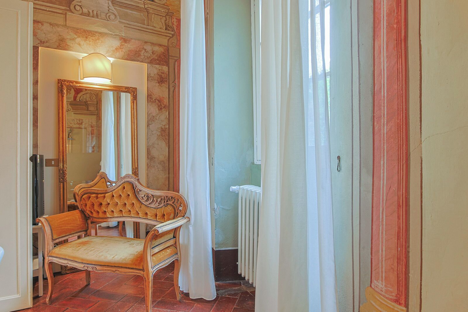 A room with a wooden chair, a mirror, and a radiator.