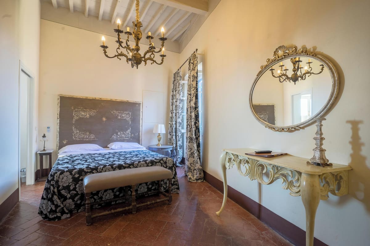Un dormitorio con una cama grande, una araña, un espejo y una consola.