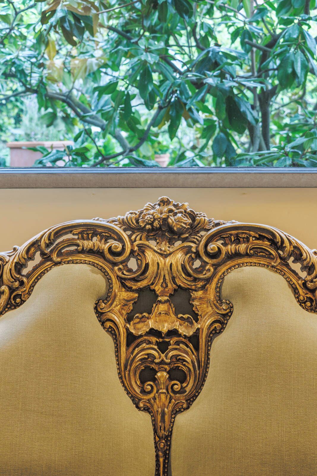A close-up of an ornate, gold-colored chair with intricate carvings.
